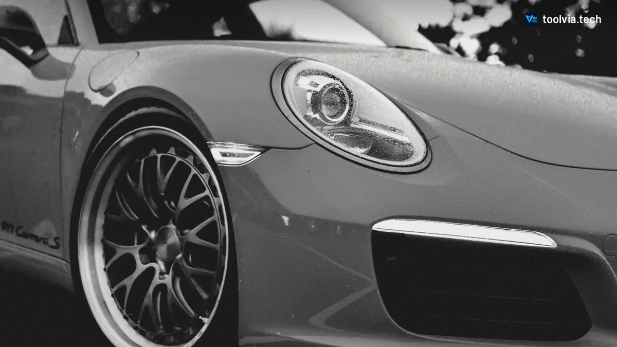 Black and white close-up of a Porsche 911 Carrera S headlight and front wheel